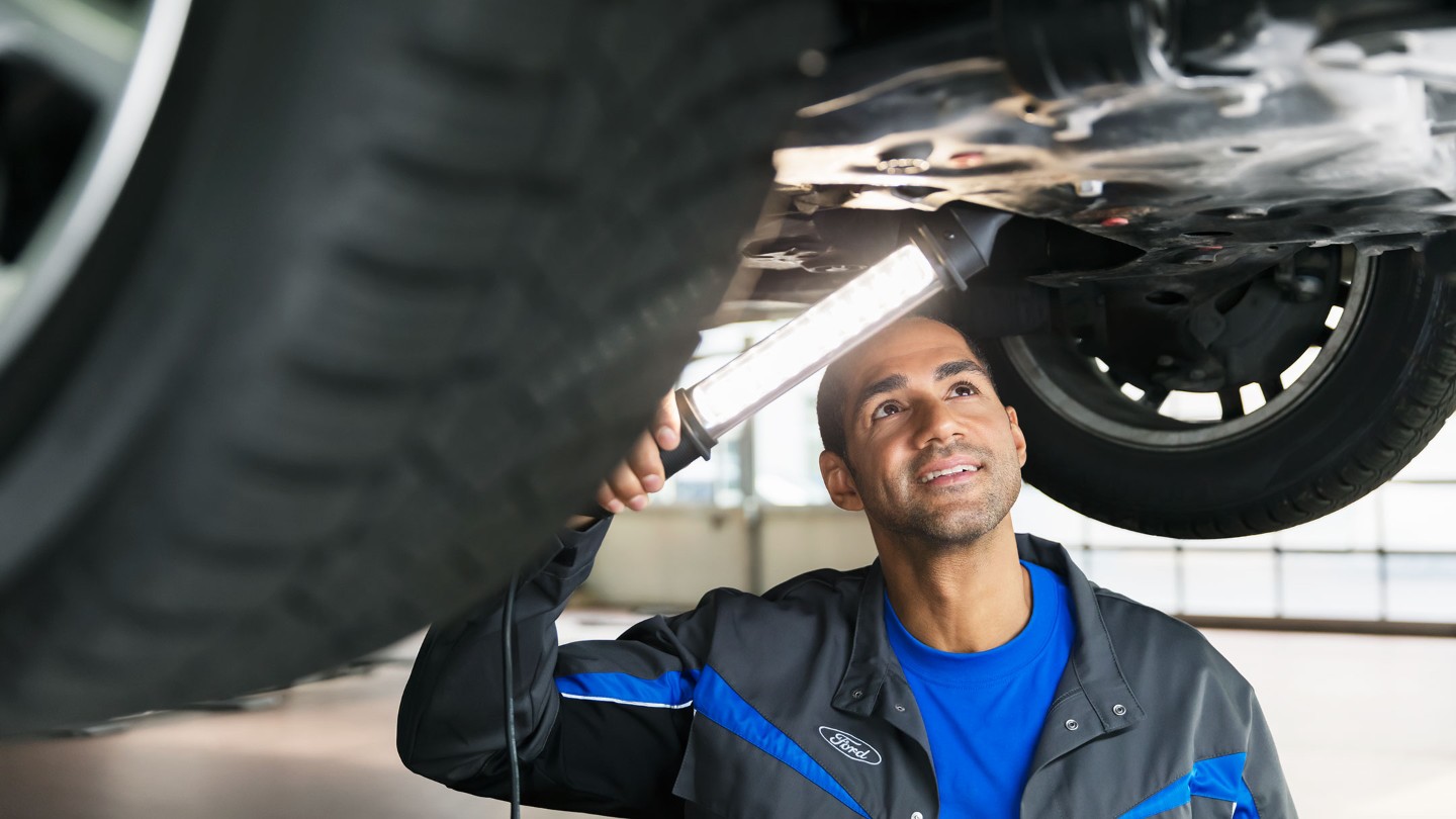 Ford service member checking bottom of car