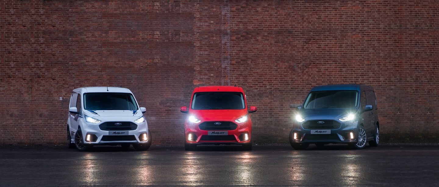 3 Ford Transt Connect Vans parked against a brick wall. 