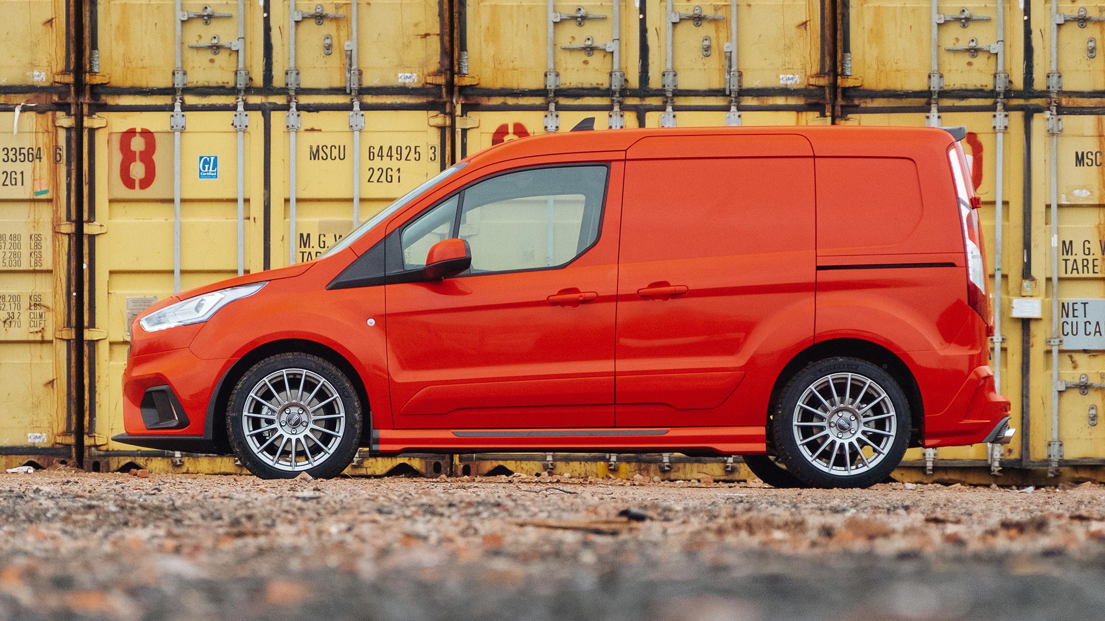 Side-view of the Ford Transit Connect MS-RT parked against a wall of sea containers.