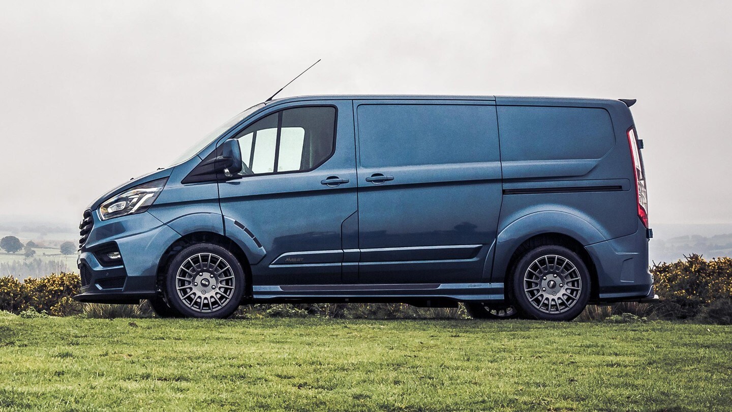 Side view of a Ford Transit Custom MS-RT Van parked on grass in a countryside scene