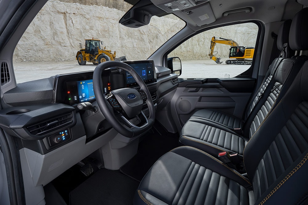 Vedere din interior a unei furgonete Ford Transit Custom, care prezintă tabloul de bord, volanul și scaunele.