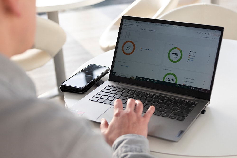 Persoană care revizuiește un tablou de bord Ford Pro Telematics pe un laptop, cu diverși indicatori care prezintă diferite valori legate de performanțele flotei.