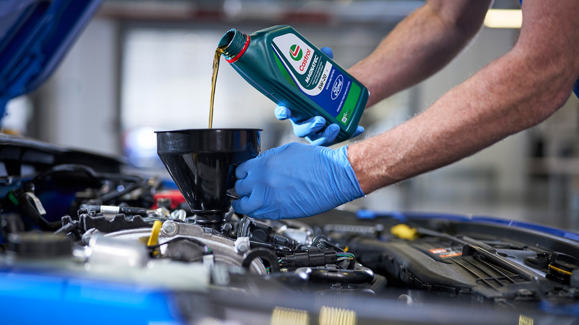 Mechanic pouring engine oil into a car engine.