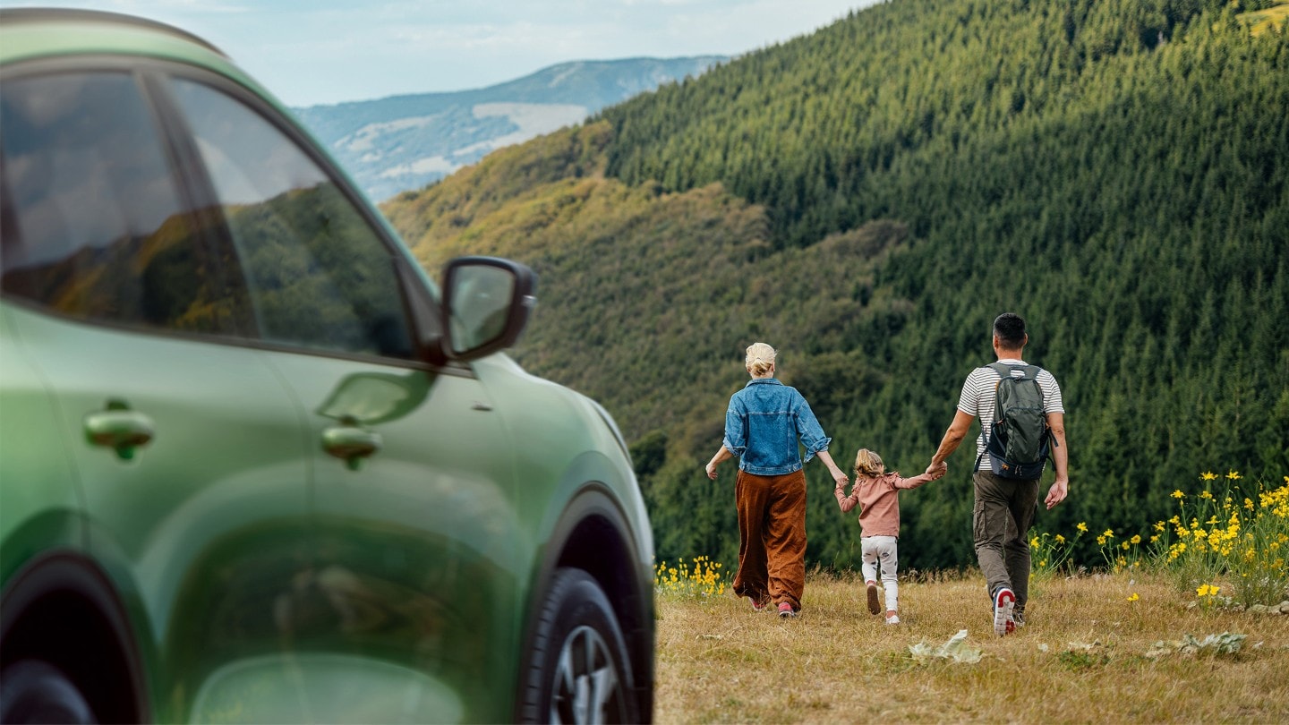 O familie care se plimbă în natură, lângă un Ford Kuga de culoare verde
