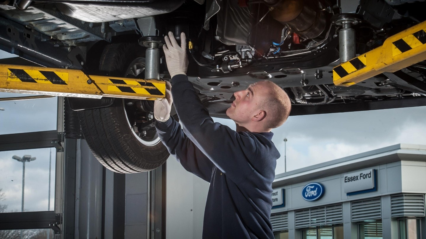 Ford service person inspecting bottom of a Ford car