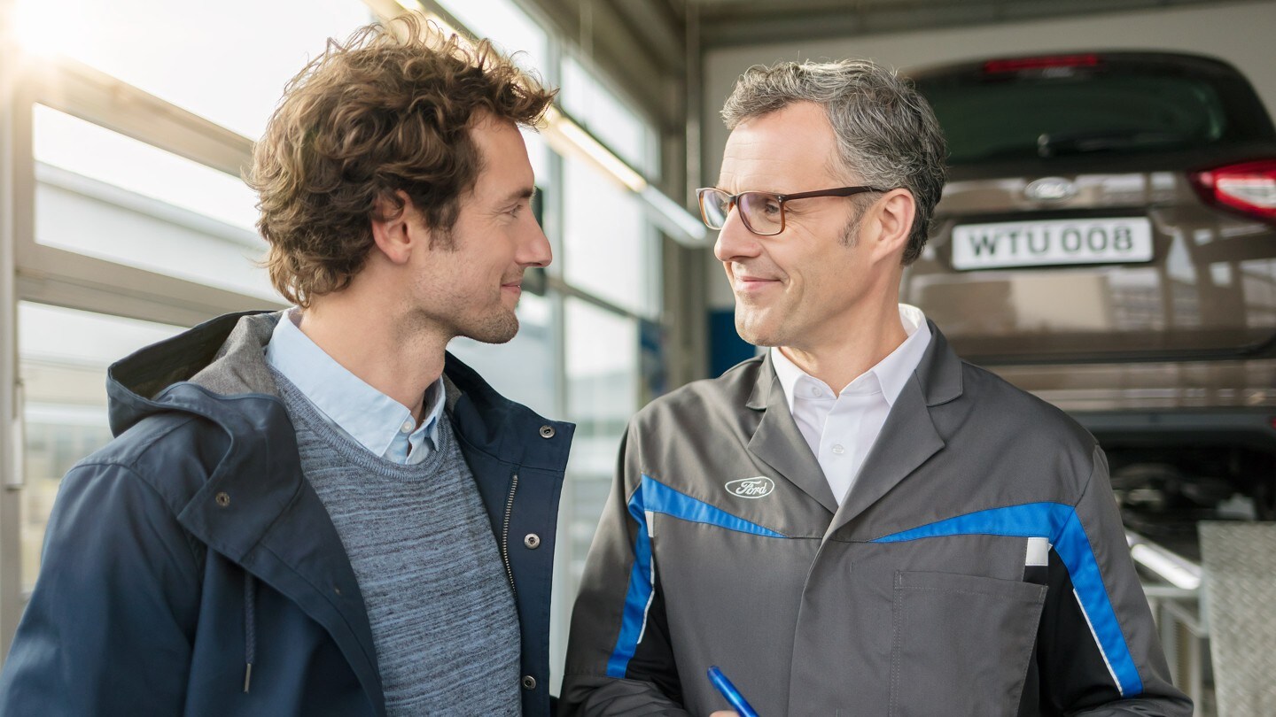 Technician and customer having conversation in a workshop