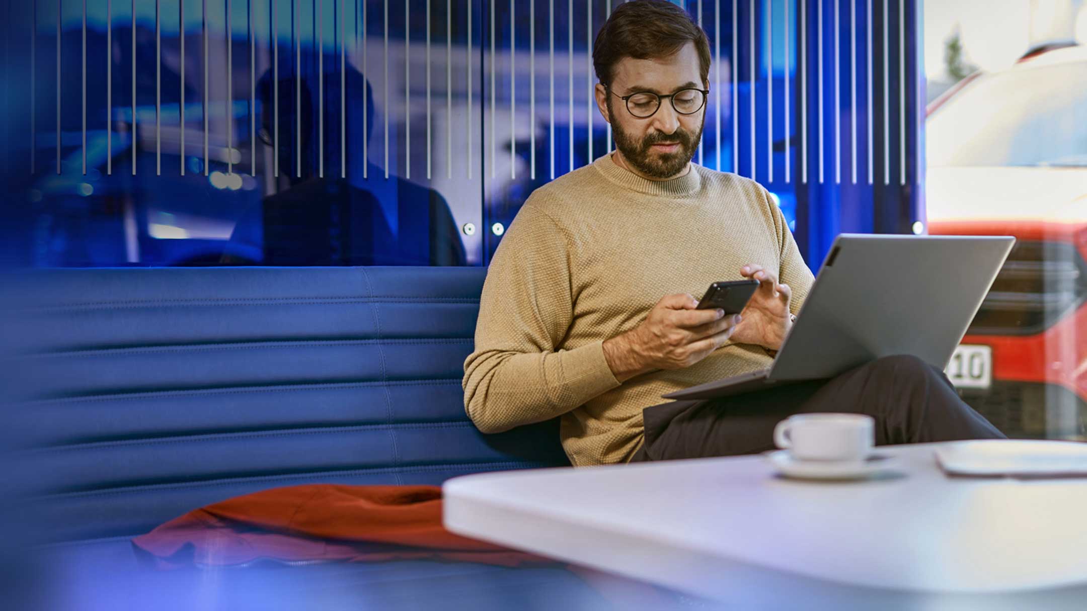 O persoană stă într-un birou modern cu un laptop și un smartphone.