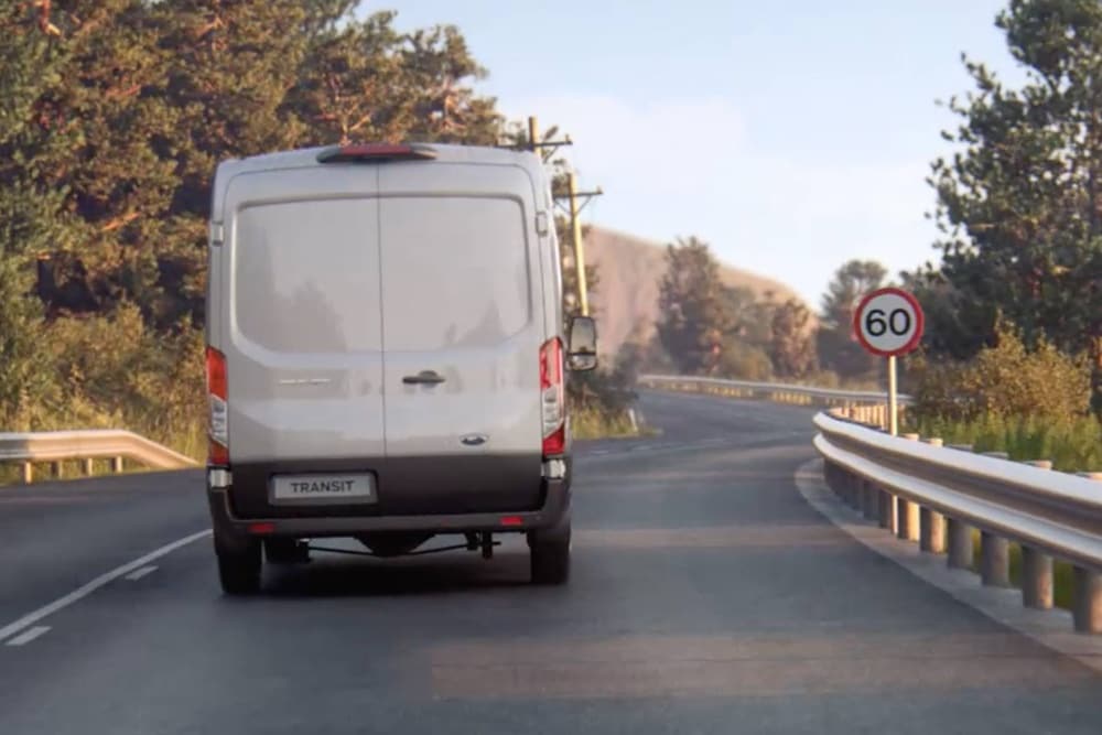 Ford Transit Van driving on the road with traffic sign viewed from back