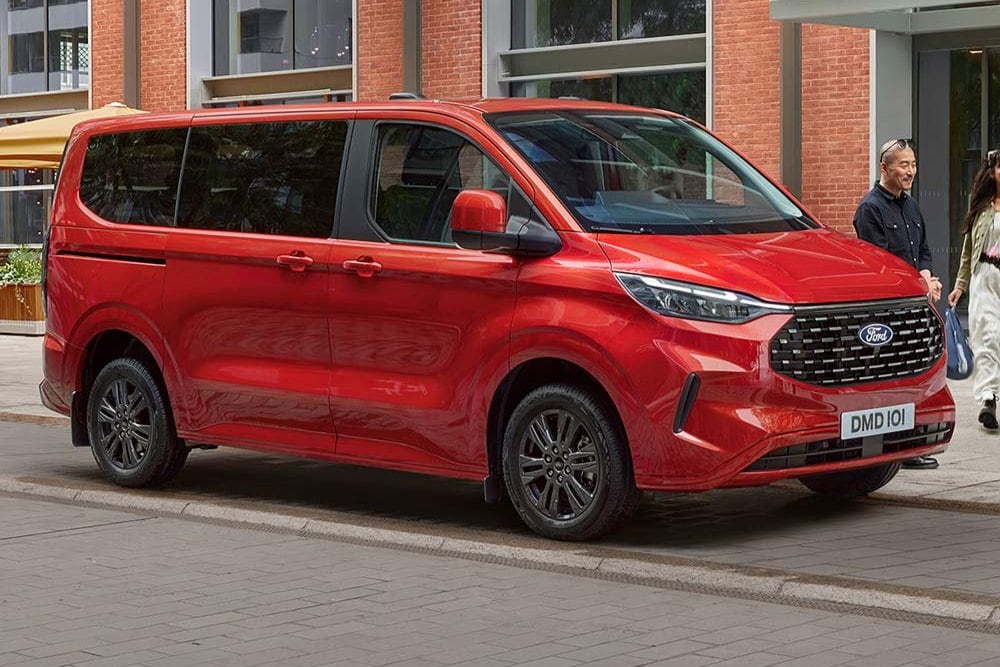 Un Ford Tourneo Custom roșu este parcat pe o stradă din oraș.