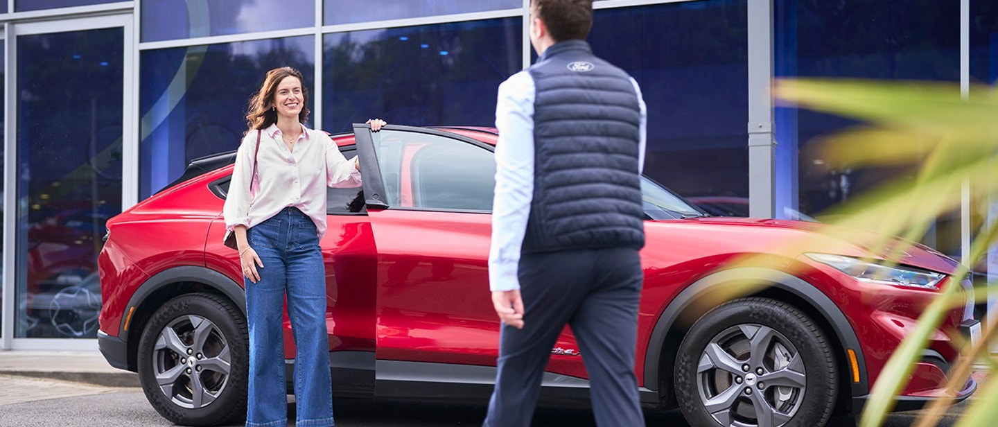 Service employee and customer standing under the car at workshop